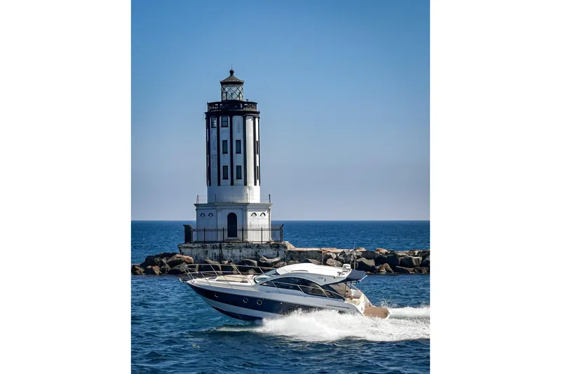  Yacht Photos Pics 2014 Beneteau Gran Turismo 38 yacht cruising near a lighthouse on a sunny day.