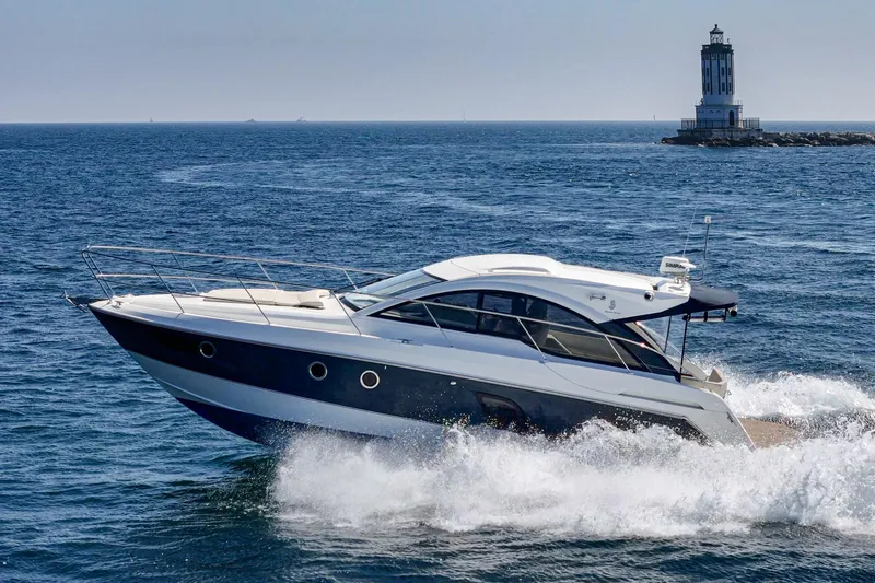  Yacht Photos Pics 2014 Beneteau Gran Turismo 38 yacht cruising near a lighthouse on open sea.