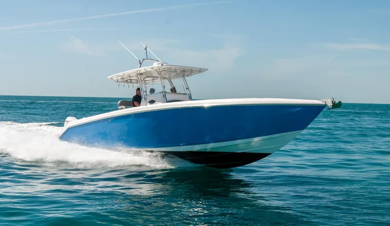  Yacht Photos Pics A blue speedboat cruising on open water under a clear sky.