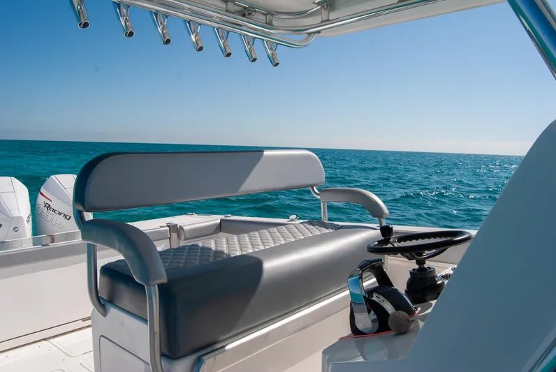  Yacht Photos Pics Boat interior with steering wheel and seating, overlooking calm ocean under clear blue sky.