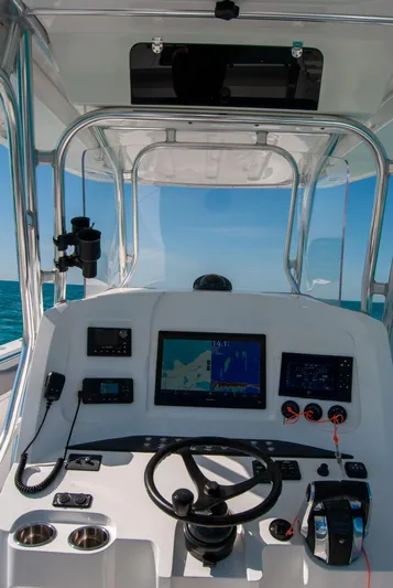 Yacht Photos Pics Boat cockpit with navigation screens, steering wheel, and controls, under clear blue sky.