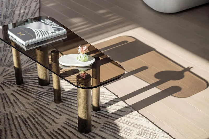  Yacht Photos Pics Modern glass coffee table with decorative items, casting shadows on a patterned rug.