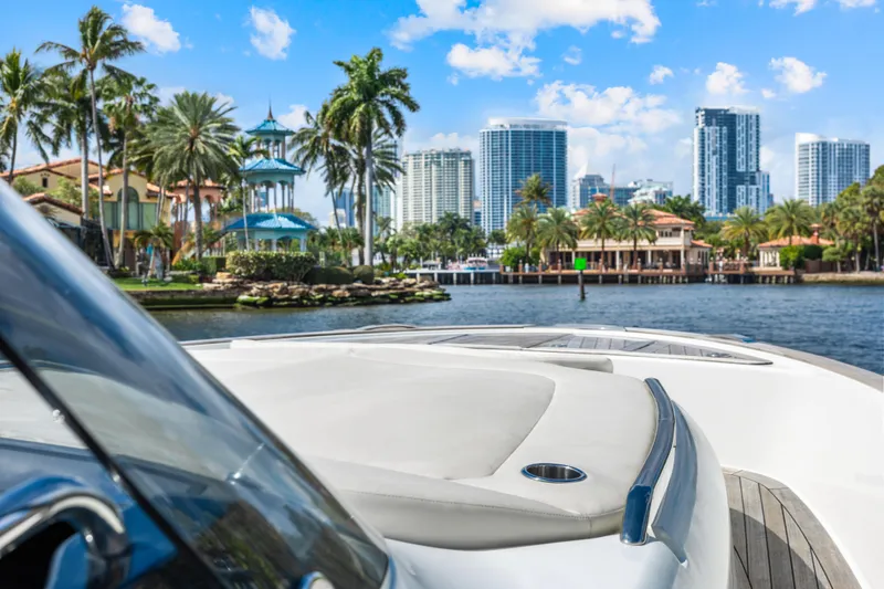  Yacht Photos Pics 2024 Solaris Power 44 yacht cruising near a tropical city skyline with palm trees.