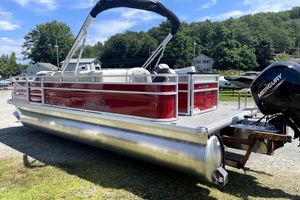 2026 Sun Tracker Fishin' Barge 22 DLX pontoon boat with Mercury engine, parked outdoors.