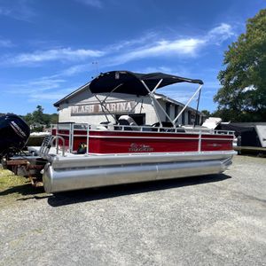 2026 Sun Tracker Fishin' Barge 22 DLX pontoon boat at marina, featuring Mercury outboard motor.
