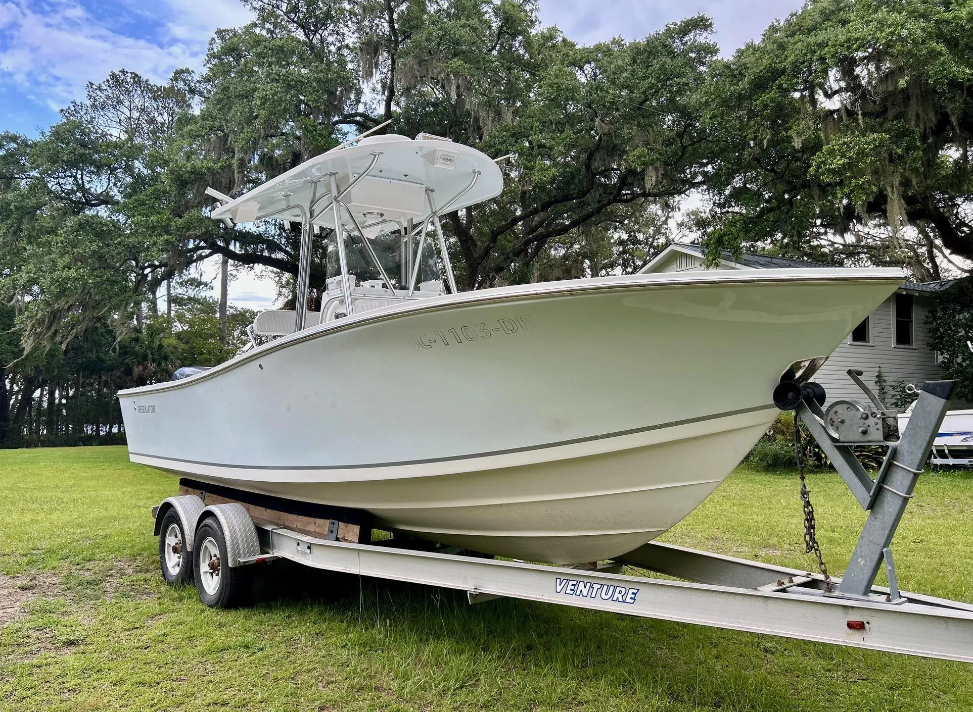 2000 Regulator 23' Center Console boat on trailer, parked on grass with trees in background.
