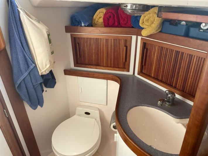 Caribou Yacht Photos Pics Compact boat bathroom with wooden cabinets, towels, and a sink. Sabre 402, 2001 model.