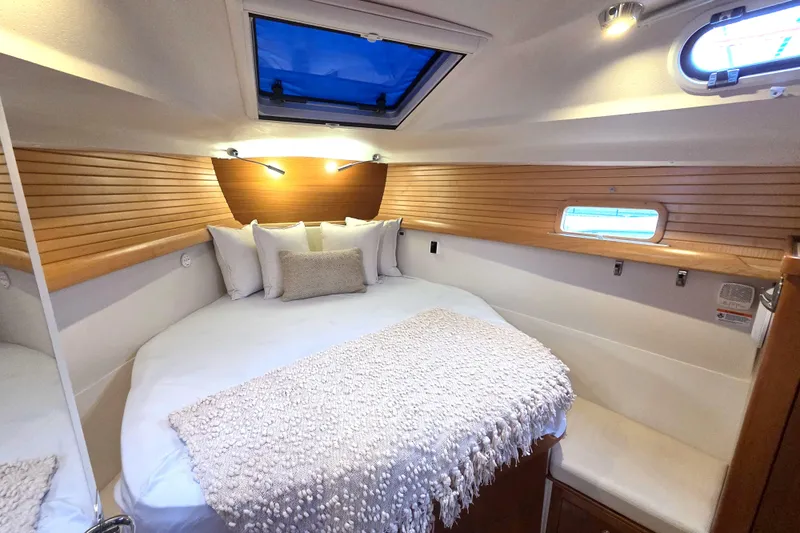 Here & Now Yacht Photos Pics Luxurious cabin interior of 2021 Catalina 445 sailboat with cozy bedding and wood paneling.