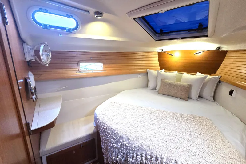 Here & Now Yacht Photos Pics Luxurious interior cabin of 2021 Catalina 445 yacht with cozy bedding and elegant wood paneling.