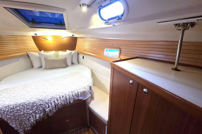 Here & Now Yacht Photos Pics Luxurious cabin interior of 2021 Catalina 445 yacht with cozy bed and wooden accents.