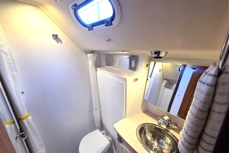 Here & Now Yacht Photos Pics 2021 Catalina 445 yacht bathroom with sink, mirror, and porthole window.