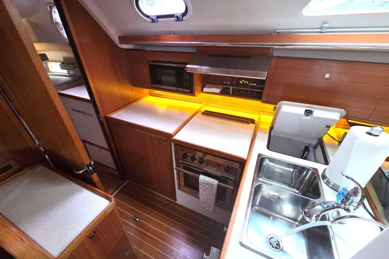Here & Now Yacht Photos Pics Modern kitchen in 2021 Catalina 445 yacht with wood cabinetry and stainless steel sink.