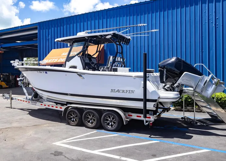  Yacht Photos Pics 2023 Blackfin 272 CC boat on trailer, parked outside blue building.