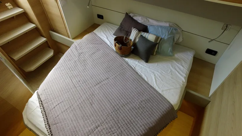 Tbd Yacht Photos Pics Cozy bedroom in 2025 Aventura 45 yacht with pillows and a basket.