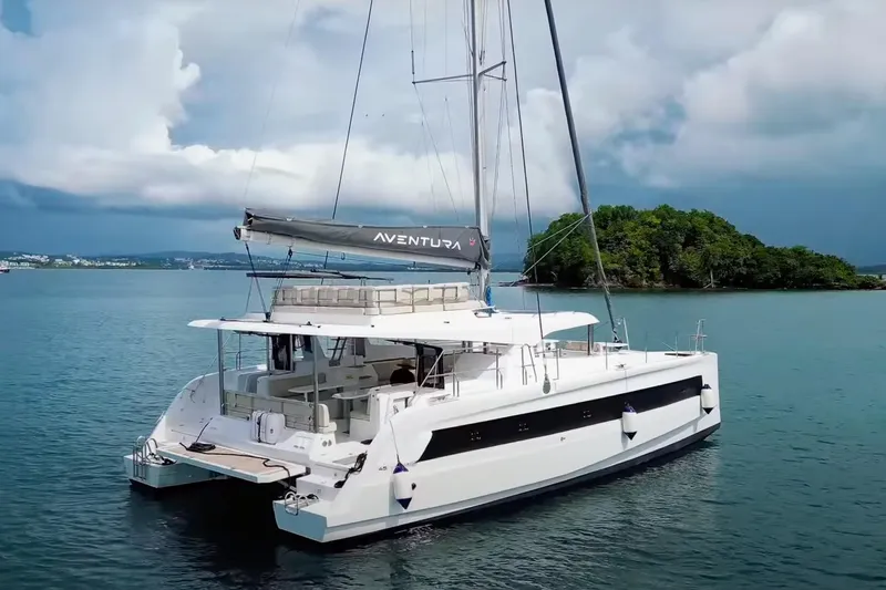 Tbd Yacht Photos Pics Aventura 45 catamaran sailing near an island, 2025 model, under cloudy skies.
