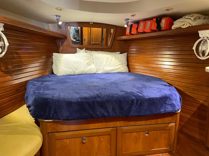 Sailing Diver Yacht Photos Pics Cozy cabin interior of 2010 Hunter 49 Aft Cockpit with wooden paneling and blue bedding.