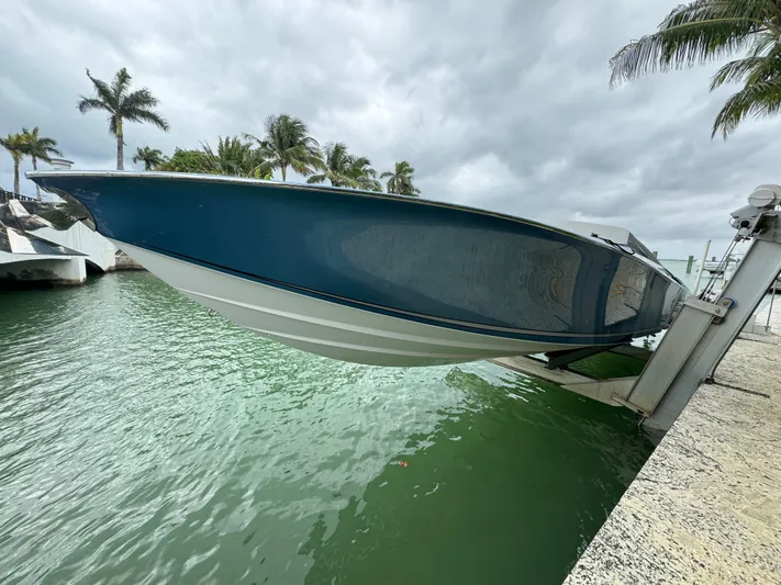  Yacht Photos Pics 2013 Nor-Tech 420 Monte Carlo boat on lift, surrounded by palm trees and water.