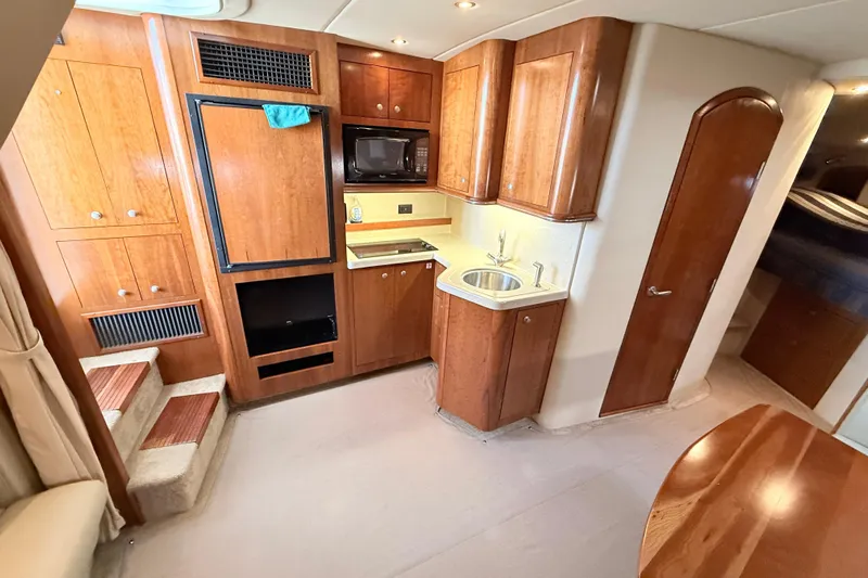 Ursula Yacht Photos Pics 2006 Cruisers Yachts 370 Express interior with wood cabinetry and compact kitchen area.