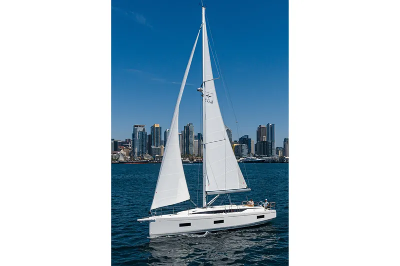 Azucar Yacht Photos Pics 2023 Bavaria C42 sailboat cruising near city skyline under clear blue sky.