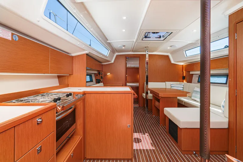 Azucar Yacht Photos Pics Modern 2023 Bavaria C42 yacht interior with wood finish, kitchen, and seating area.