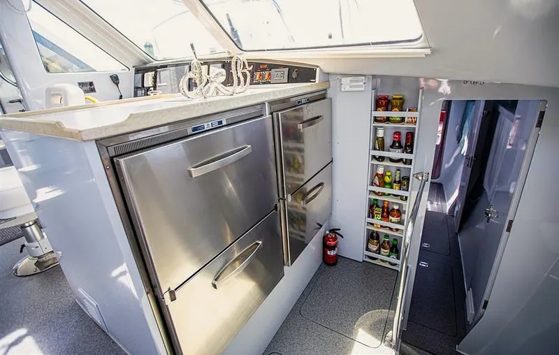 Wabisabi Yacht Photos Pics Modern yacht kitchen with stainless steel appliances, storage shelves, and a fire extinguisher. Chris White Atlantic 49.