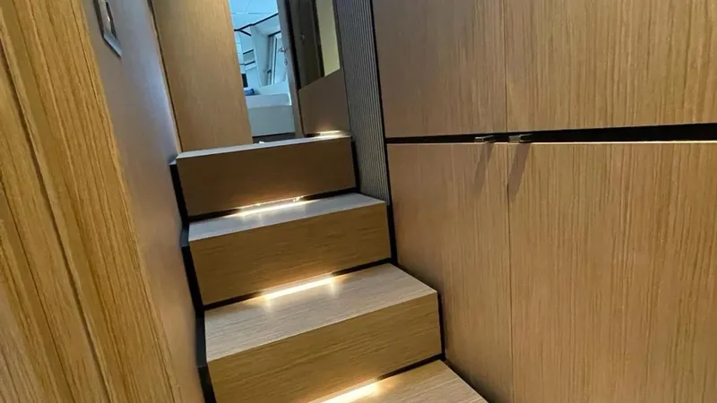  Yacht Photos Pics Interior staircase of 2023 Ferretti Yachts 720, featuring modern wood paneling and ambient lighting.