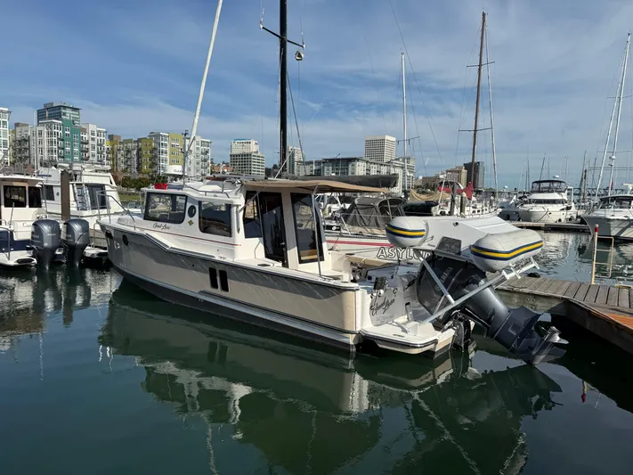  Yacht Photos Pics 2021 Ranger Tugs R-27 boat docked in a marina with cityscape background.