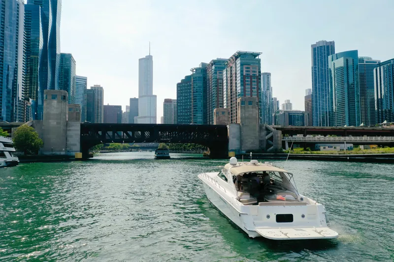  Yacht Photos Pics 1997 Sea Ray 630 Super Sun Sport yacht cruising in urban river with city skyline.