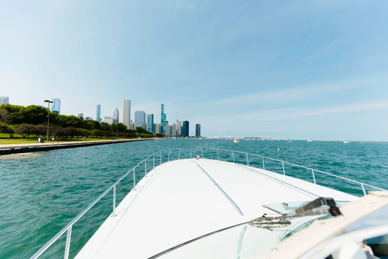  Yacht Photos Pics 1997 Sea Ray 630 Super Sun Sport cruising near a city skyline on a sunny day.