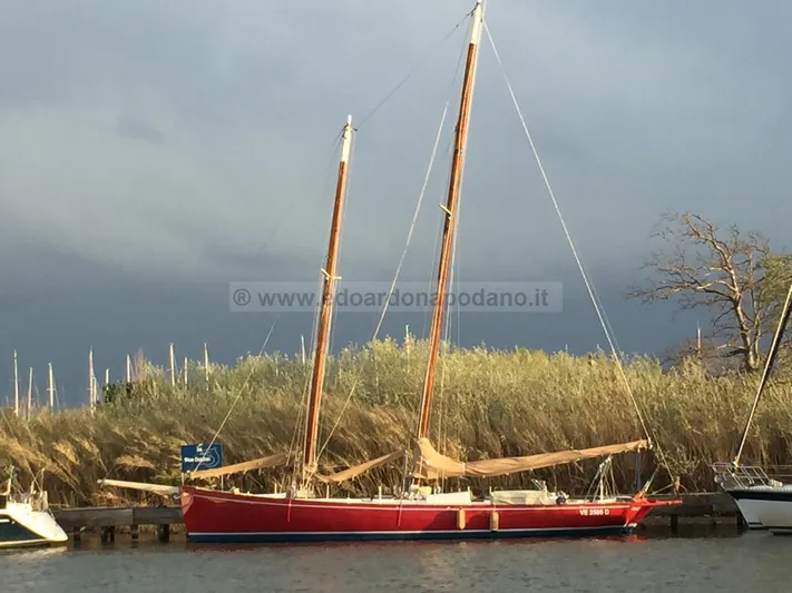  Yacht Photos Pics Classic 1984 Sciarrelli sailboat with red hull docked by reeds under cloudy sky.