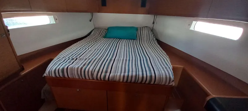 Alma Del Mar Yacht Photos Pics Cabin interior of 2014 Jeanneau Sun Odyssey 469 with striped bedding and teal pillow.