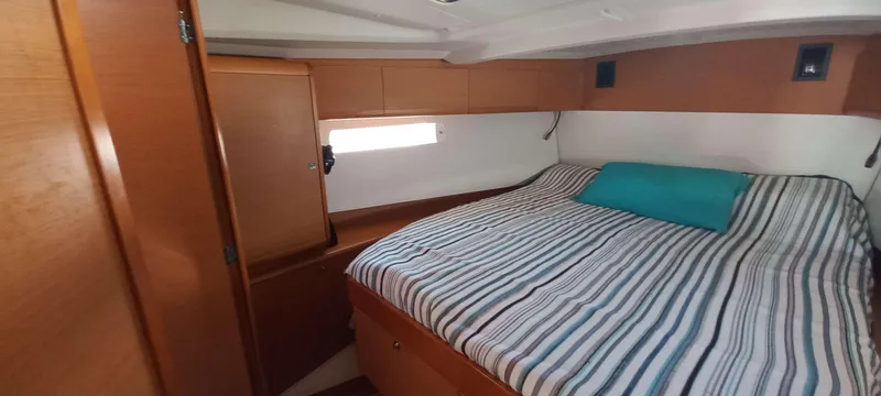 Alma Del Mar Yacht Photos Pics Interior cabin of 2014 Jeanneau Sun Odyssey 469 with striped bedding and wooden finish.