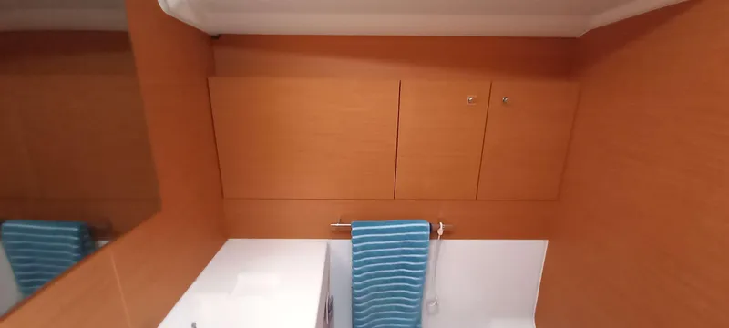 Alma Del Mar Yacht Photos Pics Interior of 2014 Jeanneau Sun Odyssey 469 bathroom with wooden cabinets and blue towel.