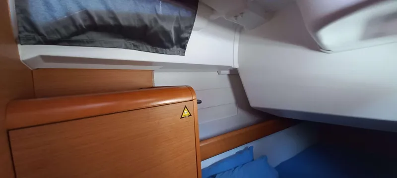 Alma Del Mar Yacht Photos Pics Interior cabin of 2014 Jeanneau Sun Odyssey 469 sailboat, featuring wood paneling and blue bedding.