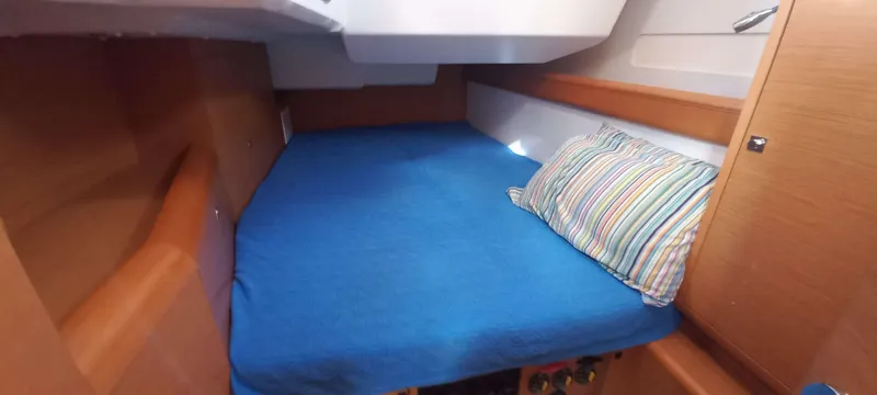 Alma Del Mar Yacht Photos Pics Cozy cabin interior of 2014 Jeanneau Sun Odyssey 469 with blue bedding and striped pillow.
