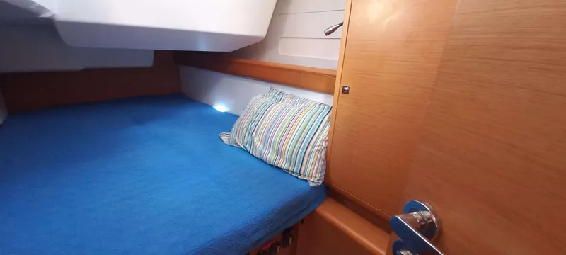 Alma Del Mar Yacht Photos Pics Cozy cabin interior of 2014 Jeanneau Sun Odyssey 469 with blue bedding and striped pillow.