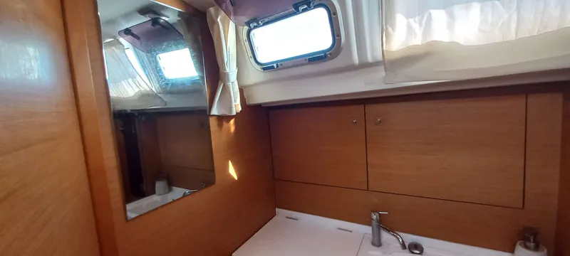 Alma Del Mar Yacht Photos Pics Interior of 2014 Jeanneau Sun Odyssey 469 yacht bathroom with wooden cabinets and mirror.