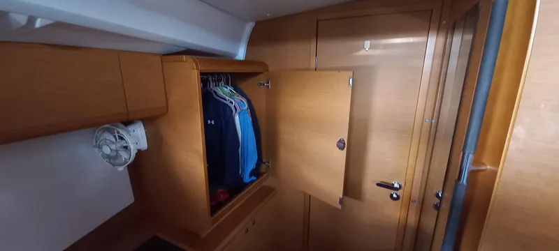 Alma Del Mar Yacht Photos Pics 2014 Jeanneau Sun Odyssey 469 cabin with wooden wardrobe and clothes hanging inside.