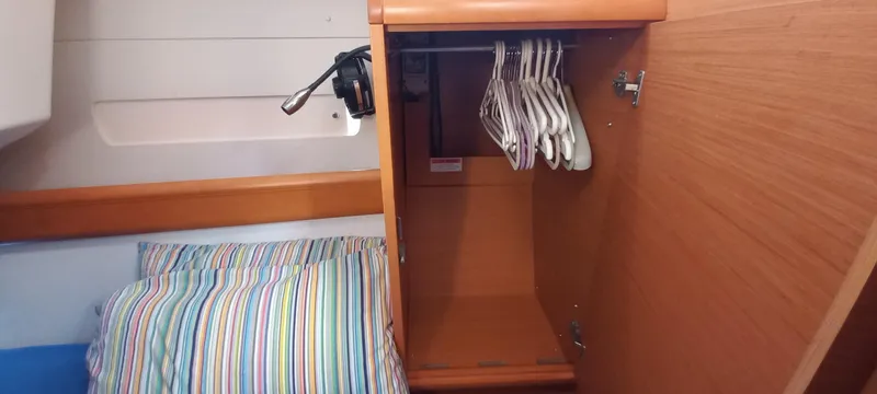 Alma Del Mar Yacht Photos Pics Cabin interior of 2014 Jeanneau Sun Odyssey 469 with open closet and striped bedding.