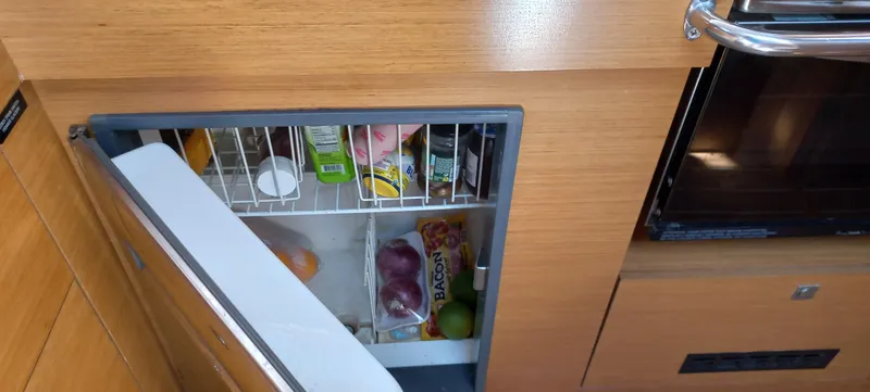 Alma Del Mar Yacht Photos Pics Refrigerator inside 2014 Jeanneau Sun Odyssey 469 yacht, stocked with various food items.