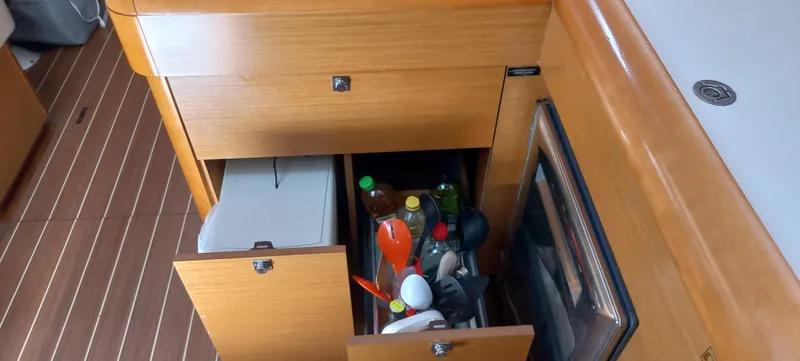 Alma Del Mar Yacht Photos Pics Interior storage of 2014 Jeanneau Sun Odyssey 469 yacht with open drawers and kitchen items.