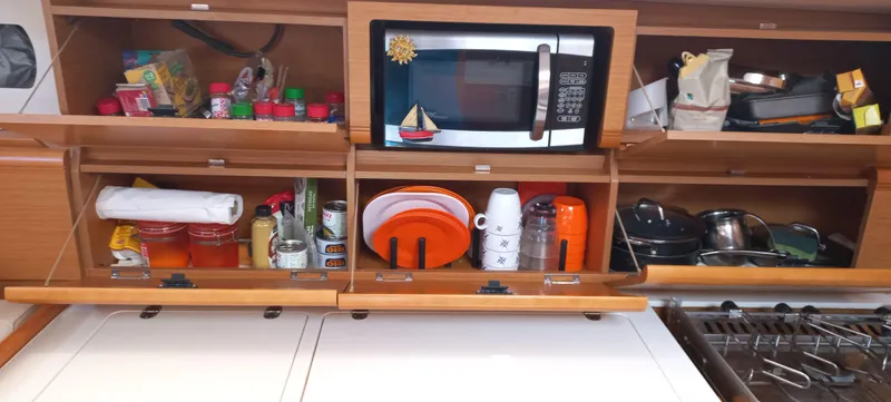 Alma Del Mar Yacht Photos Pics Kitchen storage in a 2014 Jeanneau Sun Odyssey 469 yacht, featuring a microwave and organized shelves.