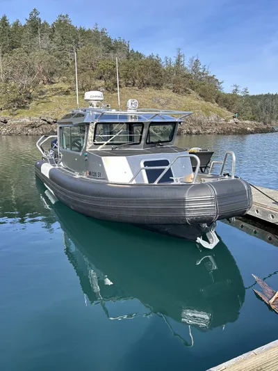  Yacht Photos Pics 2021 Life Proof 25 Full Cabin boat docked on calm water, surrounded by lush greenery.