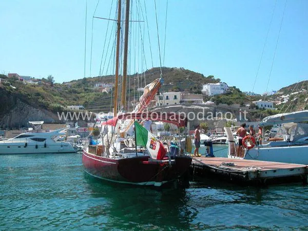  Yacht Photos Pics Classic 1984 Sciarrelli sailboat docked in a scenic marina with hills in the background.