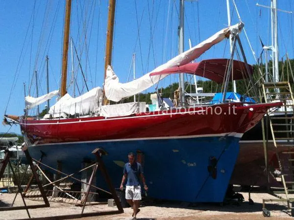  Yacht Photos Pics Classic 1984 Sciarrelli sailboat with red hull and white sails in a boatyard.