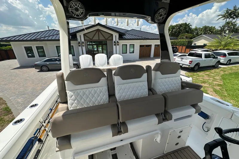  Yacht Photos Pics 2018 Edgewater 370 CC boat with luxurious seating, parked near a modern house.