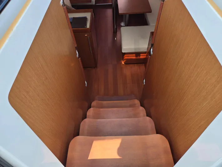 Sabrina Yacht Photos Pics Interior view of 2013 Beneteau Oceanis 41 yacht, featuring wooden stairs and cozy seating area.