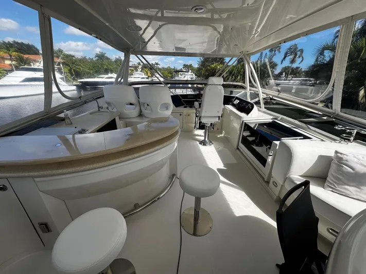 Sylvia Yacht Photos Pics Luxurious 2006 Marquis 65 yacht interior with seating and helm, docked by palm trees.