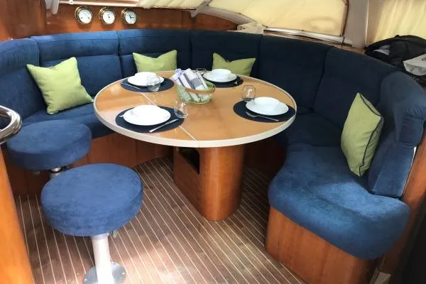 Southern Pearl Yacht Photos Pics Luxurious 2001 Privilege 435 yacht interior with blue seating, wooden table, and green cushions.