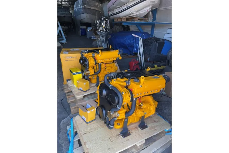 Southern Pearl Yacht Photos Pics Yellow marine engines in a workshop, with boats in the background.